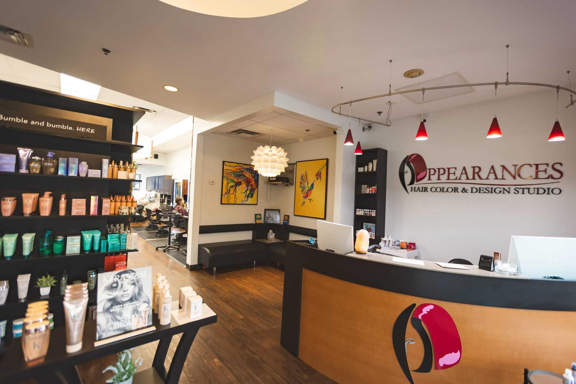 Hair salon interior with products on shelves, reception counter, and vibrant wall art.